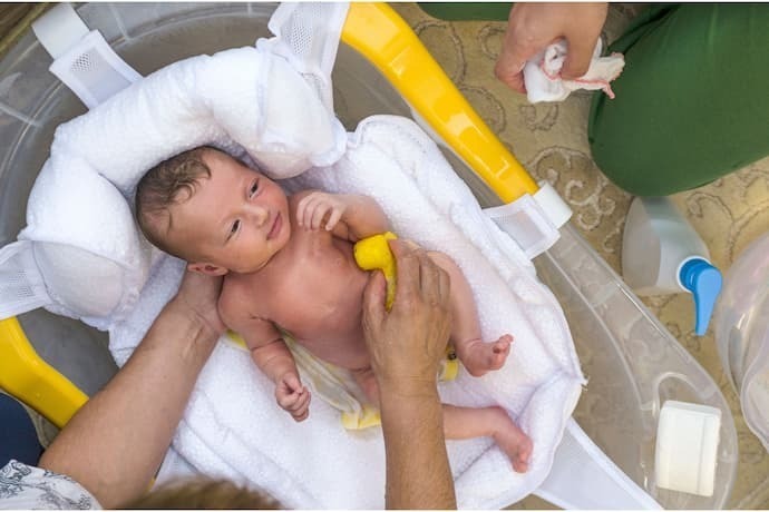 Bebê na banheira com almofada para banho branca.