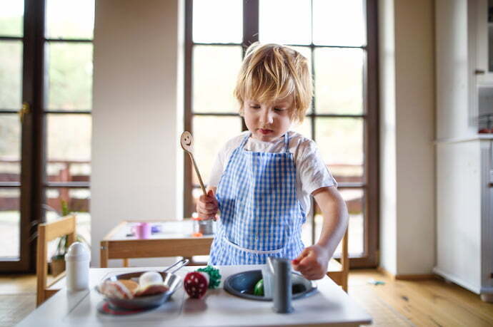 Criança brincando na cozinha de brinquedo