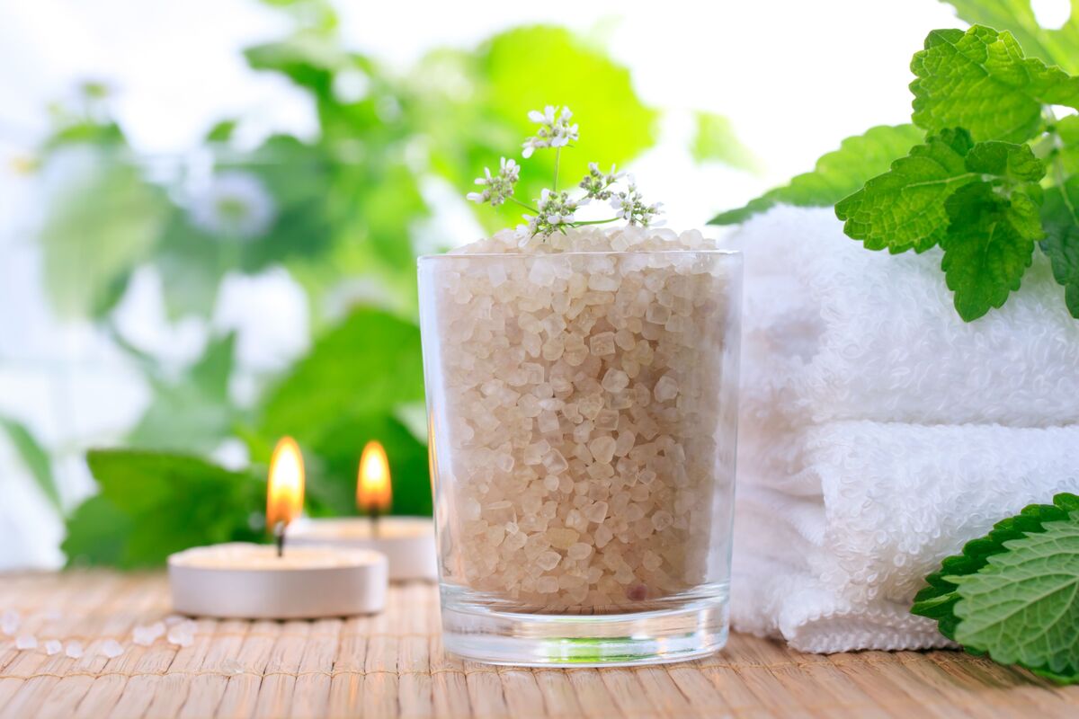 Copo com sais de banho e algumas velas de fundo