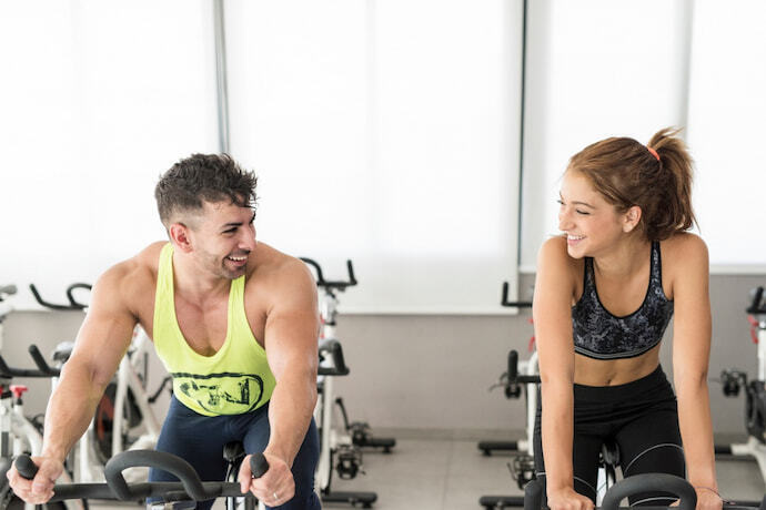 Duas pessoas treinando em uma bicicleta de spinning