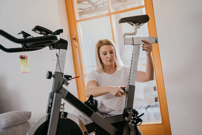 Mulher mexendo no ajuste da bicicleta de spinning