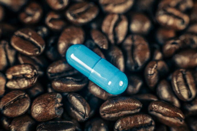 Capsula de cafeína e muitos grãos de café