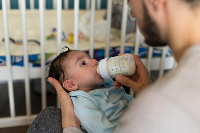 Pai dando mamadeira para bebê