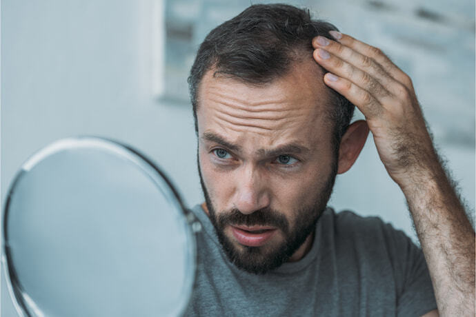 Homem olhando o cabelo no espelho