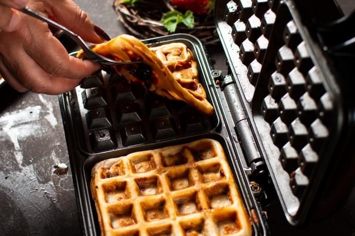 Alguém fazendo waffle na máquina de waffle