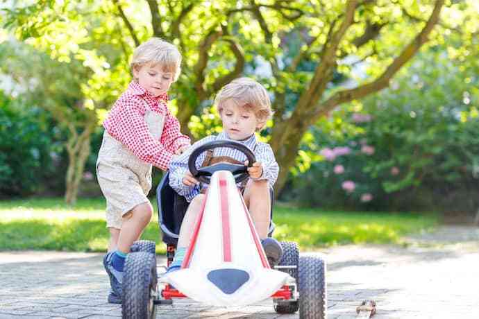 Duas crianças brincando em carrinho com pedal.