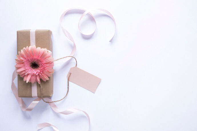 Embalagem de presente de aniversário para mãe com flor por cima.