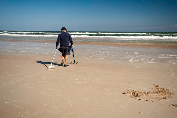 Pessoa na praia com detector de metal