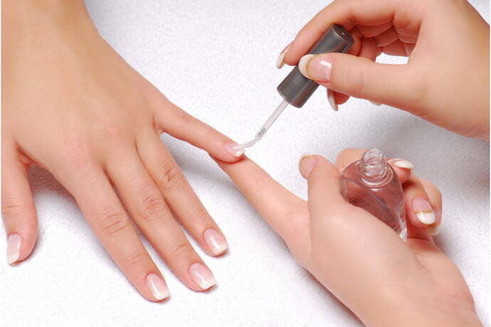 Manicure passando base para crescer unha em cliente.