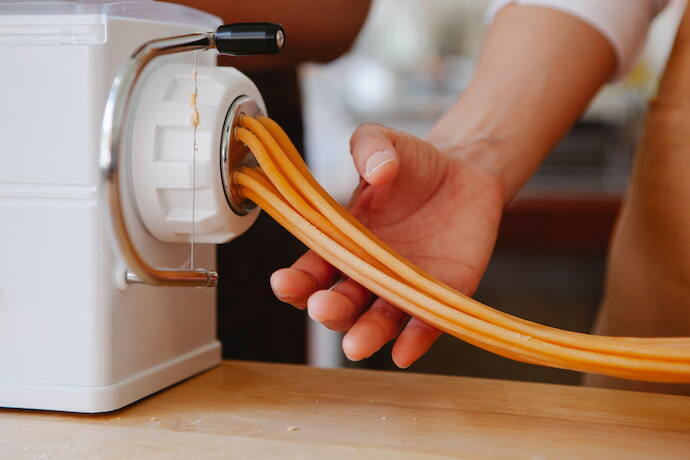 Pessoa preparando massa na máquina de macarrão elétrica