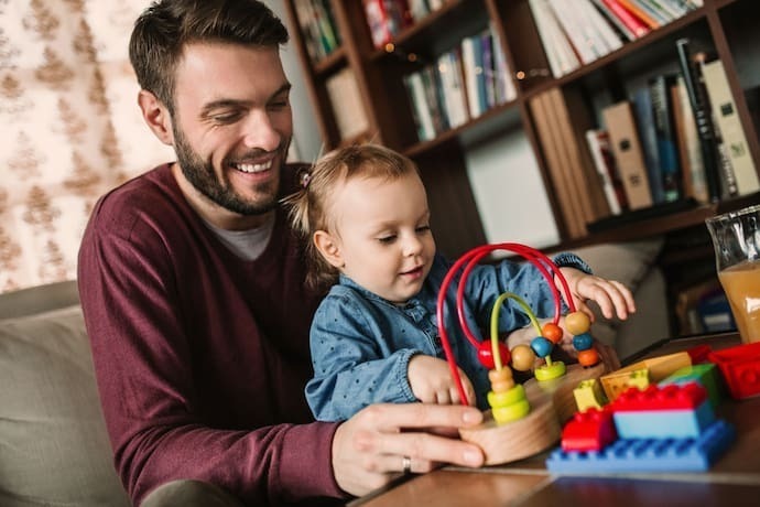 Pai brincando com bebê em brinquedo educativo.