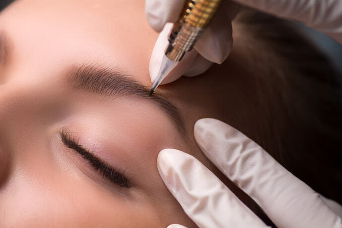 Mulher usando caneta para sobrancelha em outra mulher