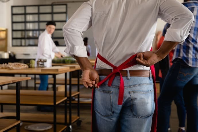 Homem amarrando avental de cozinha.