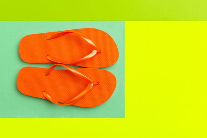 Havaiana laranja em fundo colorido.