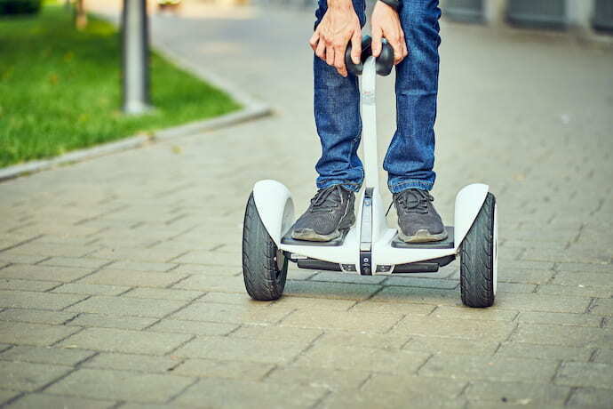 Menino andando em skate elétrico hoverboard com apoio.