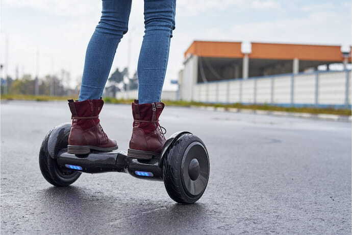 Menina com bota andando em skate elétrico hoverboard.