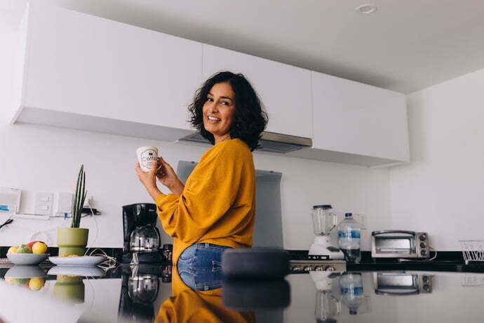 Mulher cozinhando com smart speaker  na cozinha.