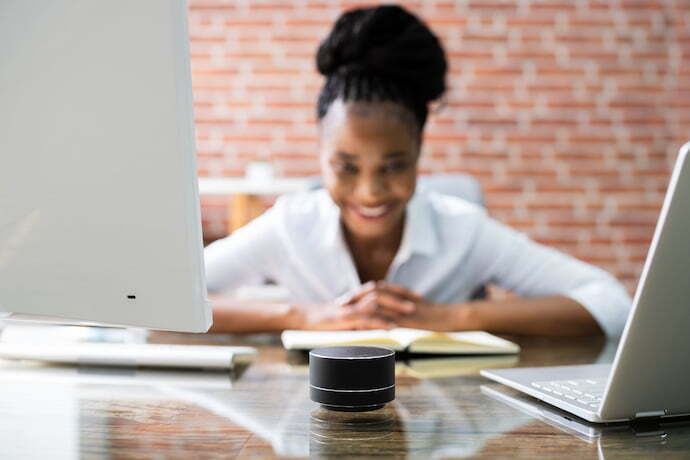 Mulher no escritório falando com smart speaker .