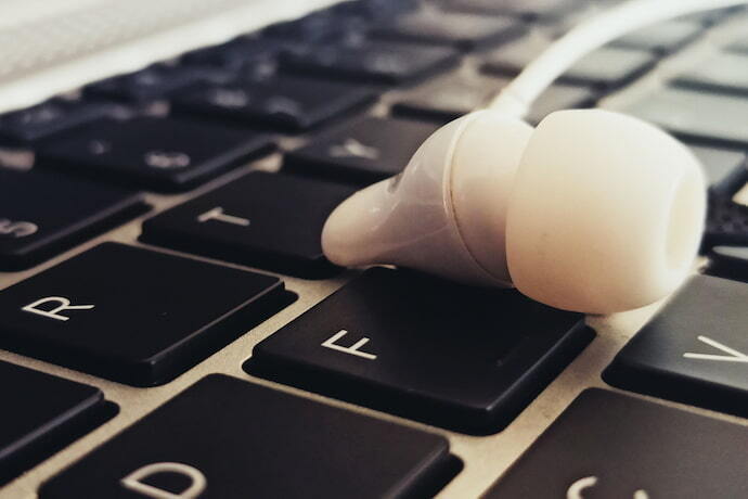 Teclado de notebook com fone em cima.