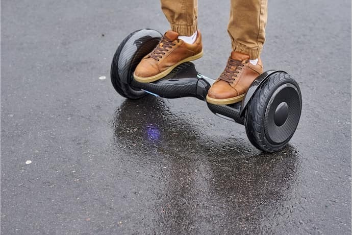 Homem andando de hoverboard inclinado para frente.