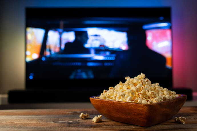 TV com Alexa passando filme e balde de pipoca na frente.