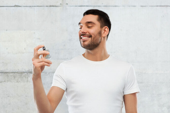 Homem sorridente passando perfume masculino.