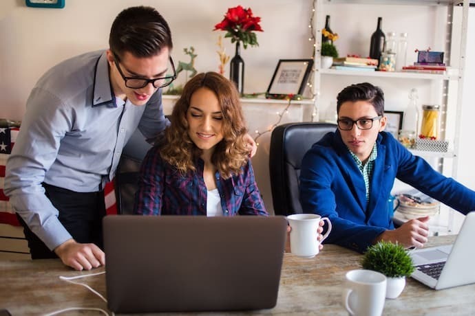 Grupo de pessoas felizes com notebook positivo no trabalho.