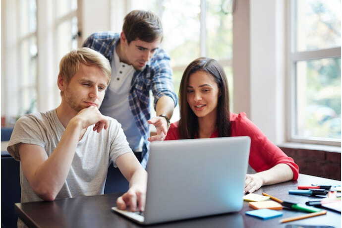 Grupo de amigos vendo notebook para edição de vídeo.