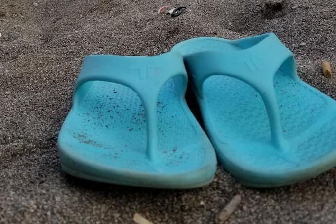 Chinelo ortopédico azul em areia.