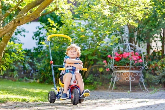 Criança brincando com triciclo infantil