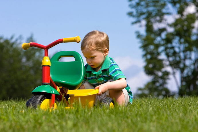 Criança brincando com triciclo infantil