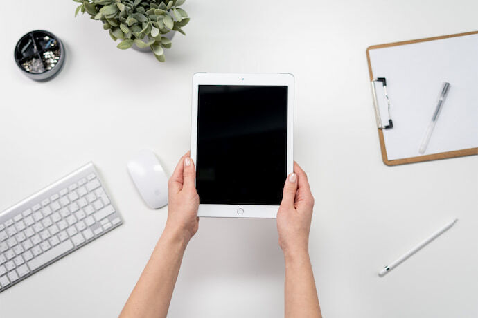 Mulher segurando iPad branco em cima da mesa de escritório