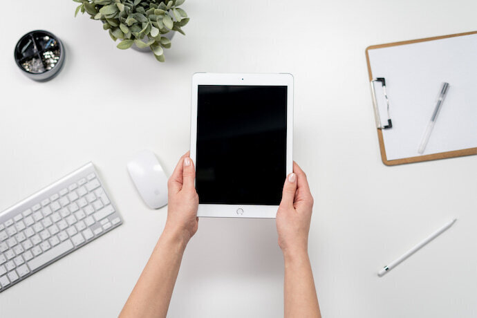 Pessoa segurando iPad branco em mesa de escritório