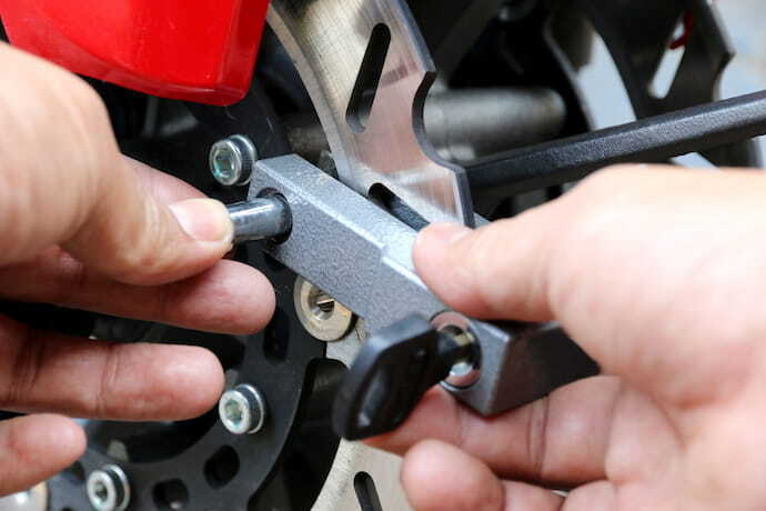 Mão de um homem trancando cadeado de roda de moto