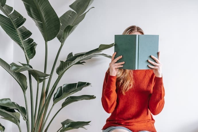 Mulher lendo livro tampando a própria cara