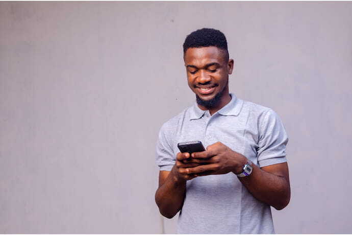 Homem sorrindo enquanto olha em seu celular