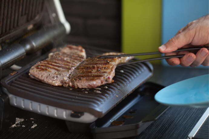 Carnes sendo preparadas em sanduicheira e grill