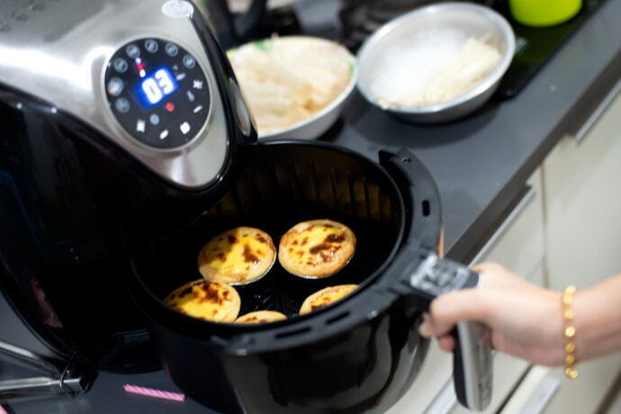 Indivíduo verificando a funcionalidade da fritadeira elétrica na cor preta.