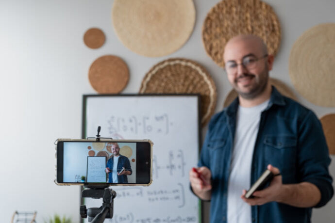 Homem gravando vídeo como celular com o auxílio do tripé