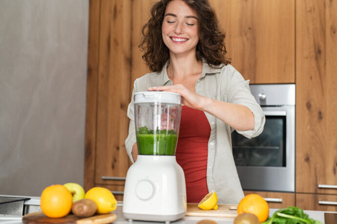 Mulher preparando uma receita no liquidificador sobre bancada 