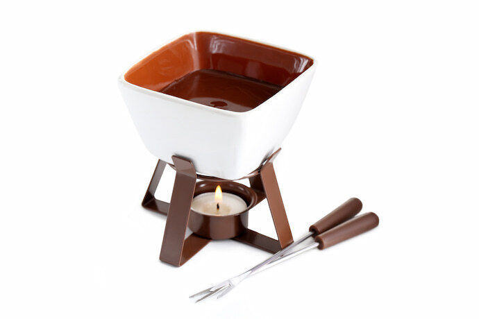 Fondue de cerâmica cheia de chocolate isolado em um fundo branco.