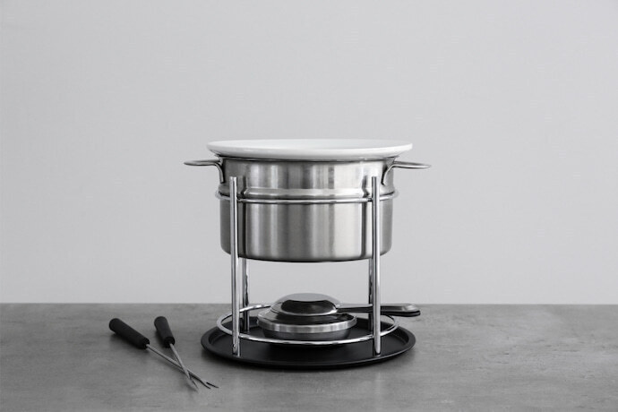 Fondue de inox sobre a mesa cinza.