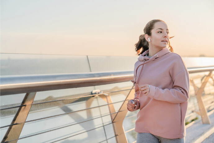 Mulher com fones de ouvido correndo pelo ponte