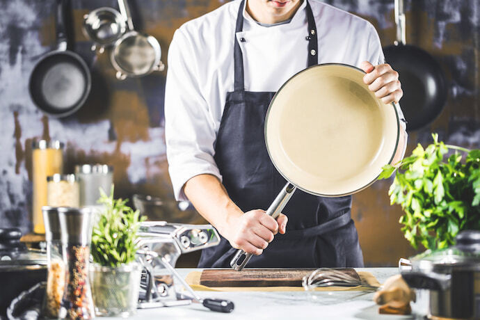 Um cozinheiro segurando uma panela de cerâmica 