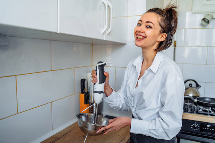 Mulher em pé preparando massa em um mixer na cozinha.