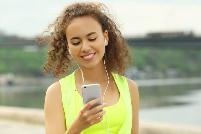 Mulher ouvindo música em fones de ouvido na rua.