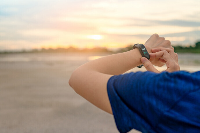 Pessoa com smartband no pulso ao fundo o amanhecer