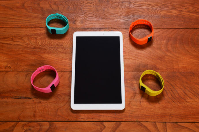 Quatro smartband de diferentes cores e tablet