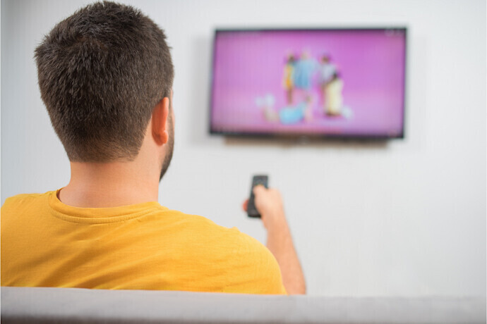 Alguém assistindo televisão e uma parede branca