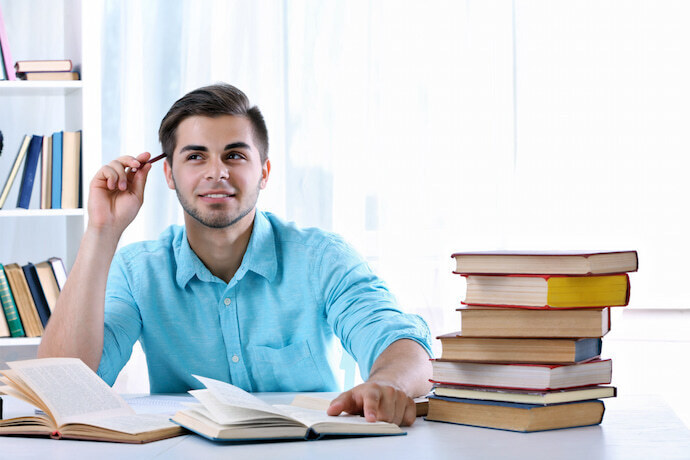 Homem lendo livros em uma mesa.